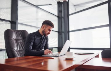 Ofiste dizüstü bilgisayarla çalışan resmi kıyafetli modern bir işadamı..