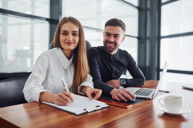 Ofiste masanın yanında duran, resmi giyinmiş kadın ve erkek portresi..