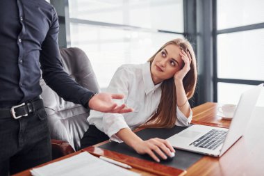 Resmi giyinmiş bir kadın ve bir adam ofis içinde masa başında birlikte çalışıyorlar..