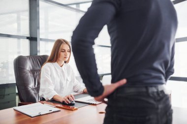 Dikiz aynası. Resmi giyinmiş bir kadın ve bir adam ofis içinde masa başında birlikte çalışıyorlar..