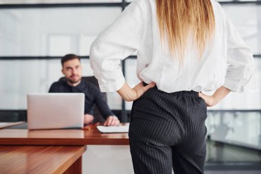 Resmi giyinmiş bir kadın ve bir adam ofis içinde masa başında birlikte çalışıyorlar..