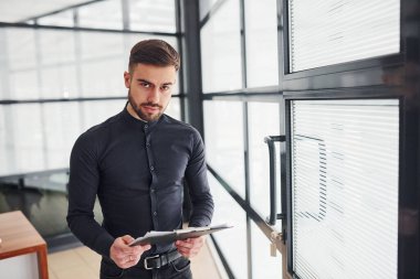 Gündüz vakti resmi giyinmiş bir ofis çalışanı evde dikiliyor..