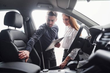 Salondaki erkek asistanın yardımıyla arabayı seçen kadın..