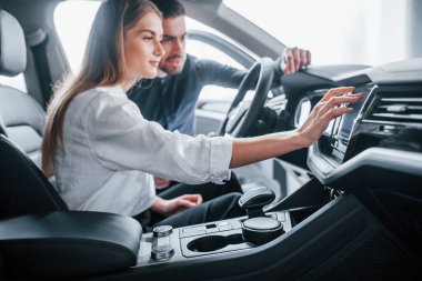 Kadın, salonda erkek asistanın yardımıyla arabayı test ediyor..