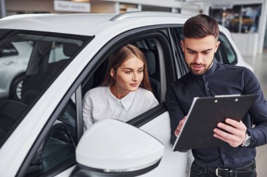 Kadın, erkek asistanın yardımıyla arabayı test ediyor. Kuaförde kapalı alandaki hareketleri gösteriyor..