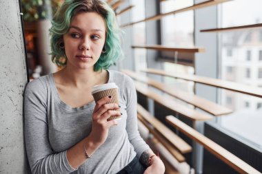 Gündüz vakti elinde bir bardak içkiyle evde duran yeşil saçlı, sıradan bir kız..