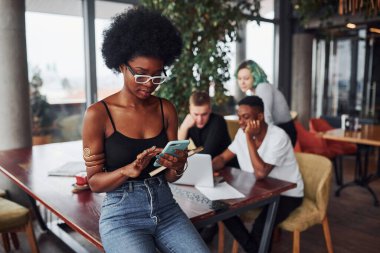 Çok ırklı ve yeşil saçlı alternatif bir kız grubunun önünde duran siyahi kadın kapalı alanda birlikte çalışıyor..