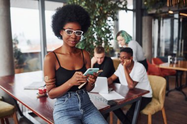 Çok ırklı ve yeşil saçlı alternatif bir kız grubunun önünde duran siyahi kadın kapalı alanda birlikte çalışıyor..