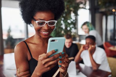 Çok ırklı ve yeşil saçlı alternatif bir kız grubunun önünde duran siyahi kadın kapalı alanda birlikte çalışıyor..