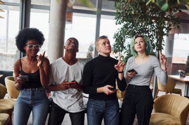 Alternatif saçlı, yeşil saçlı, etnik çeşitliliğe sahip bir grup insan içeride yan yana duruyor..