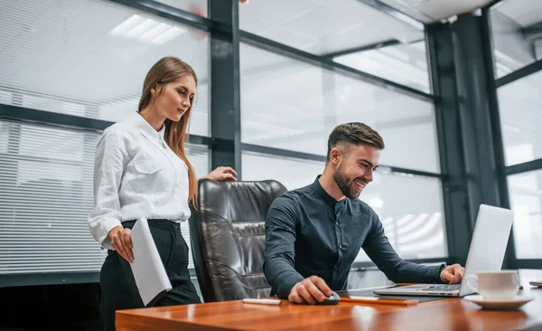 Resmi giyinmiş bir kadın ve bir adam ofis içinde masa başında birlikte çalışıyorlar..