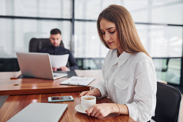 Woman and man in formal clothes working together indoors in the office by table with documents.