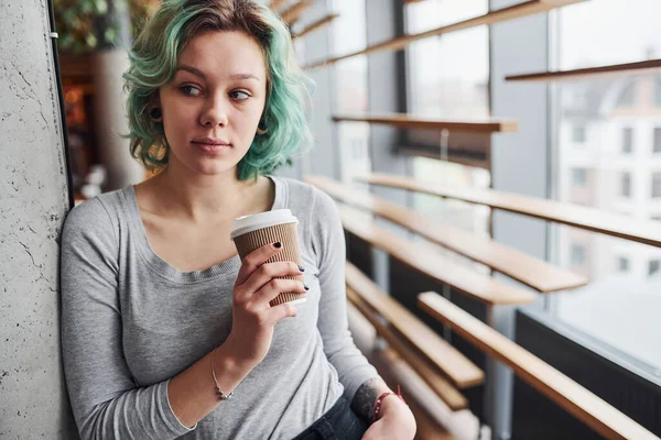 Gündüz vakti elinde bir bardak içkiyle evde duran yeşil saçlı, sıradan bir kız..