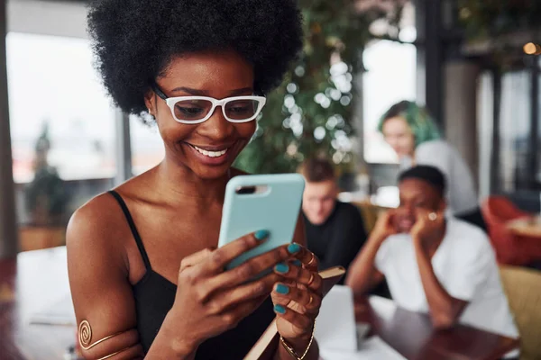 Çok ırklı ve yeşil saçlı alternatif bir kız grubunun önünde duran siyahi kadın kapalı alanda birlikte çalışıyor..