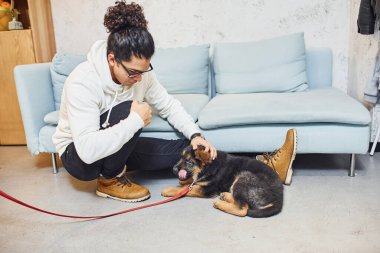 Yakışıklı, kıvırcık siyah saçlı, sevimli köpekli genç bir adam..