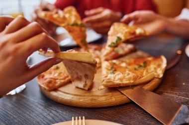 Kapalı alanda pizza yiyen ve alan insanları yakından izleyin..