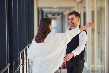 Young girl in casual clothes is with man in formal wear indoors together.