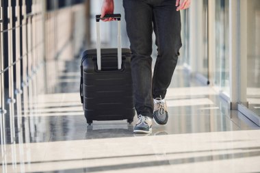 Şık giyinmiş erkek yolcuların cezalı görüntüsü havaalanı koridorunda bavullarla yürüyor..