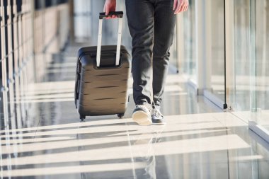 Şık giyinmiş erkek yolcuların cezalı görüntüsü havaalanı koridorunda bavullarla yürüyor..