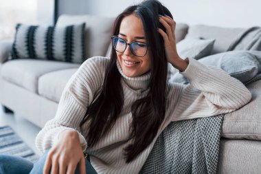 Gözlüklü güzel bir kadın evde tek başına oturuyor..