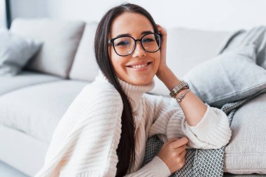 Young beautiful woman in glasses sitting at home alone.