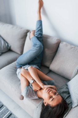 Young beautiful woman in casual clothes lying down at home alone.