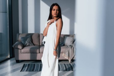 Genç, güzel esmer kız, içeride duruyor ve vücudunu beyaz havluyla örtüyor..