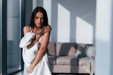 Genç, güzel esmer kız, içeride duruyor ve vücudunu beyaz havluyla örtüyor..