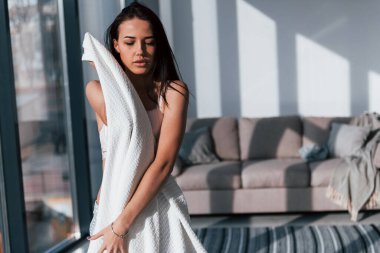 Genç, güzel esmer kız, içeride duruyor ve vücudunu beyaz havluyla örtüyor..