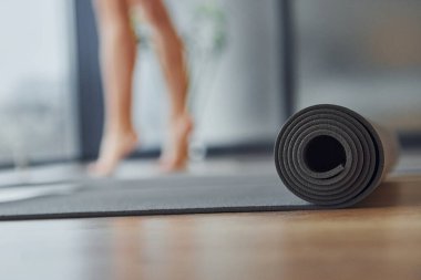Close up focused view on mat. Young woman in sportive wear and with slim body have fitness yoga day indoors.
