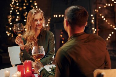 Masanın yanında oturuyor. Genç ve güzel çift evde romantik bir akşam yemeği yiyor..