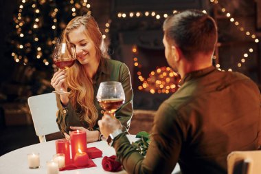 Şarap tadıyorum. Genç ve güzel çift evde romantik bir akşam yemeği yiyor..