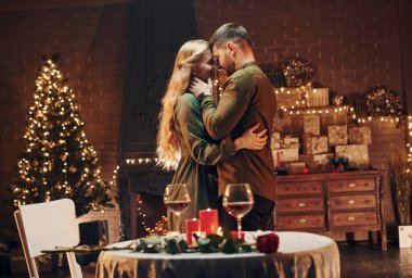 Ayakta ve dans ederek. Genç ve güzel çift evde romantik bir akşam yemeği yiyor..