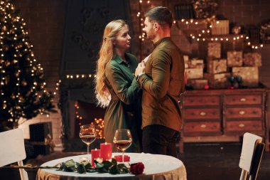 Ayakta ve dans ederek. Genç ve güzel çift evde romantik bir akşam yemeği yiyor..