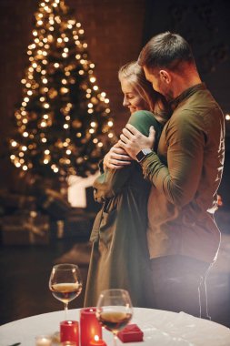 Ayakta durmak ve birbirimizi kucaklamak. Genç ve güzel çift evde romantik bir akşam yemeği yiyor..