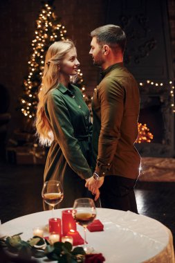 Noel süslemeli odada dikiliyorum. Genç ve güzel çift evde romantik bir akşam yemeği yiyor..