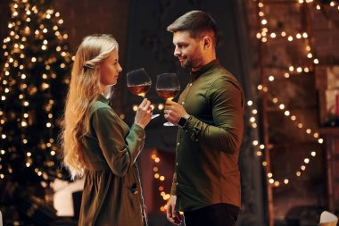 Ayakta ve elinde şarapla büyük bardaklarla. Genç ve güzel çift evde romantik bir akşam yemeği yiyor..