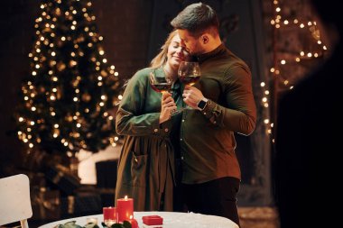 Ayakta ve elinde şarapla büyük bardaklarla. Genç ve güzel çift evde romantik bir akşam yemeği yiyor..