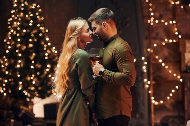 Ayakta ve elinde şarapla büyük bardaklarla. Genç ve güzel çift evde romantik bir akşam yemeği yiyor..