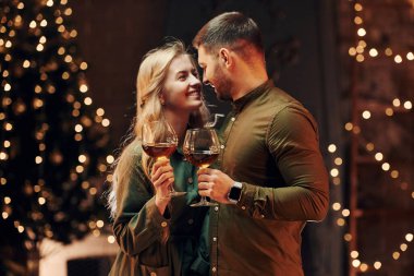 Ayakta ve elinde şarapla büyük bardaklarla. Genç ve güzel çift evde romantik bir akşam yemeği yiyor..