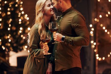 Ayakta ve elinde şarapla büyük bardaklarla. Genç ve güzel çift evde romantik bir akşam yemeği yiyor..