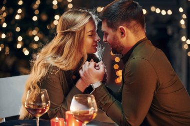 Yan görüş. Genç ve güzel çift evde romantik bir akşam yemeği yiyor..