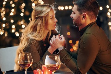 Yan görüş. Genç ve güzel çift evde romantik bir akşam yemeği yiyor..