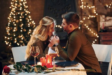 Yan görüş. Genç ve güzel çift evde romantik bir akşam yemeği yiyor..