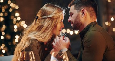 Yan görüş. Genç ve güzel çift evde romantik bir akşam yemeği yiyor..