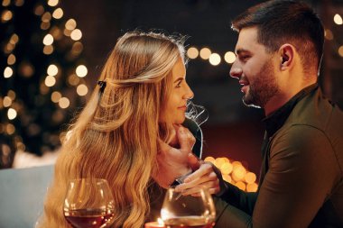 Yan görüş. Genç ve güzel çift evde romantik bir akşam yemeği yiyor..