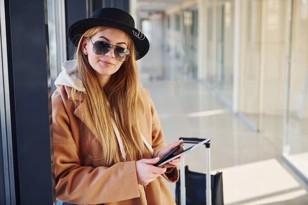 Young Woman Sunglasses Warm Clothes Hat Standing Indoors Airport Phone — стоковое фото
