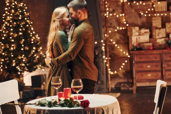 站在装饰过的圣诞房间里 年轻貌美的夫妻在室内共进浪漫晚餐 — 图库照片
