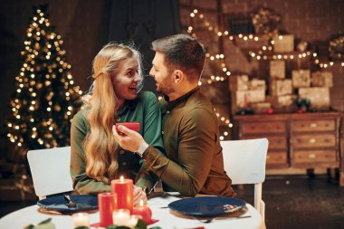 Masanın yanında oturuyor. Genç ve güzel çift evde romantik bir akşam yemeği yiyor..
