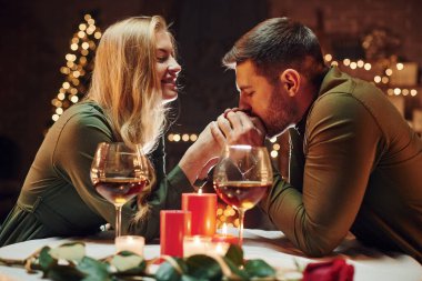 Ellerinden tutarak. Genç ve güzel çift evde romantik bir akşam yemeği yiyor..